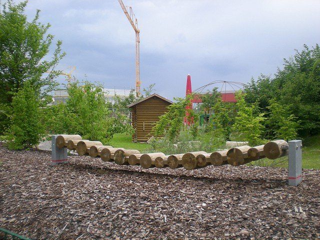 Ein hölzerner Schwebebalken in einem Park mit einem Kran im Hintergrund