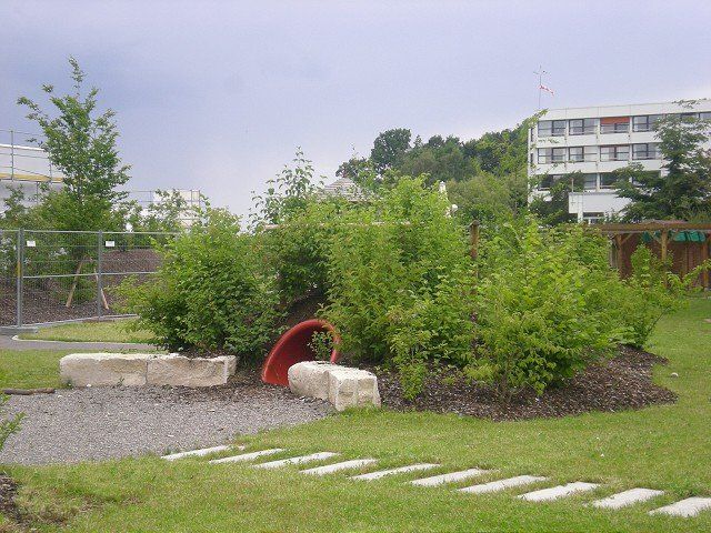 Ein Garten mit einem Zaun und einem Gebäude im Hintergrund