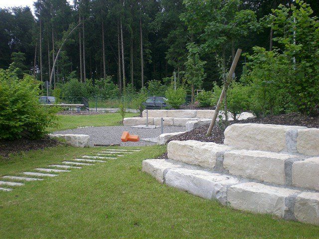 Eine Steintreppe in einer Rasenfläche mit Bäumen im Hintergrund