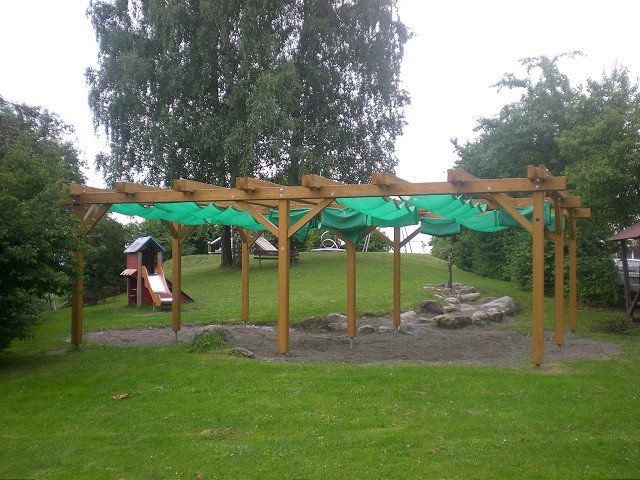 Eine Holzkonstruktion mit einer grünen Plane darauf