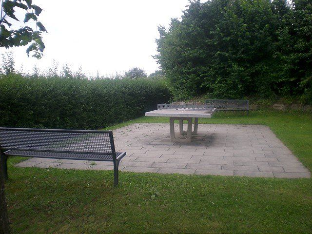 Eine Tischtennisplatte in einem Park mit einer Bank