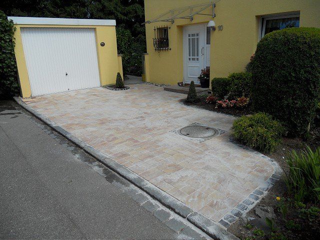 Eine Auffahrt, die zu einem gelben Haus mit einem weißen Garagentor führt