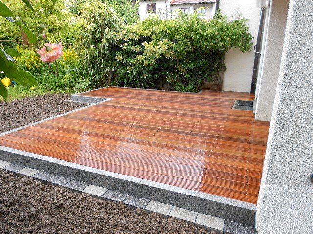 Vor einem Haus steht ein Holzdeck.