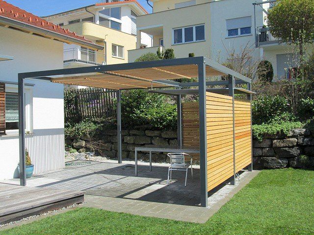 Eine Pergola mit Tisch und Stühlen vor einem Haus.