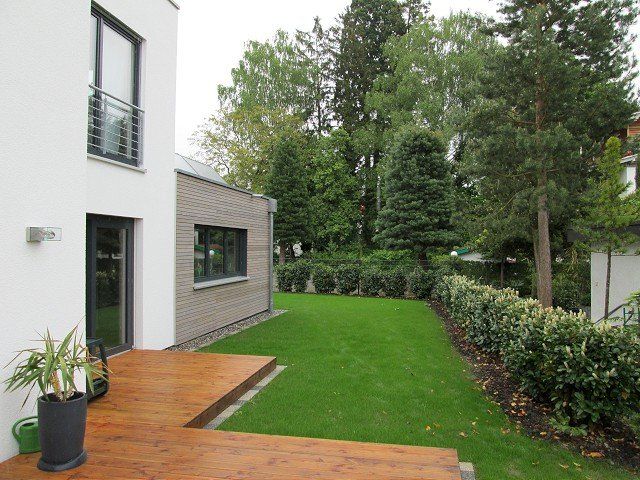 Ein Haus mit großem Rasen und Holzterrasse