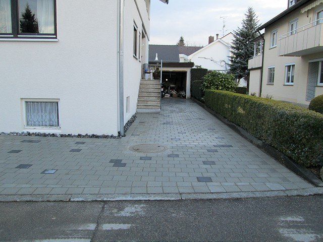 Ein weißes Haus mit einer gemauerten Auffahrt, die zu einer Garage führt