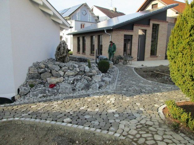 Ein Mann in einer grünen Jacke steht vor einem Haus