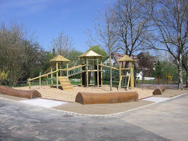 Ein Holzspielplatz in einem Park mit Bäumen im Hintergrund