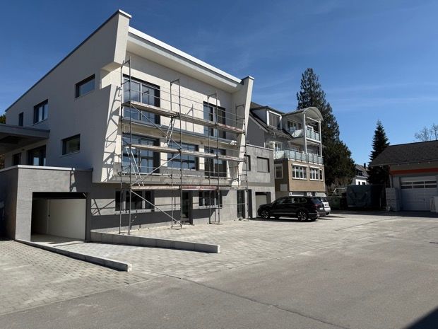 Ein grünes Rohr liegt im Dreck neben einem Haus