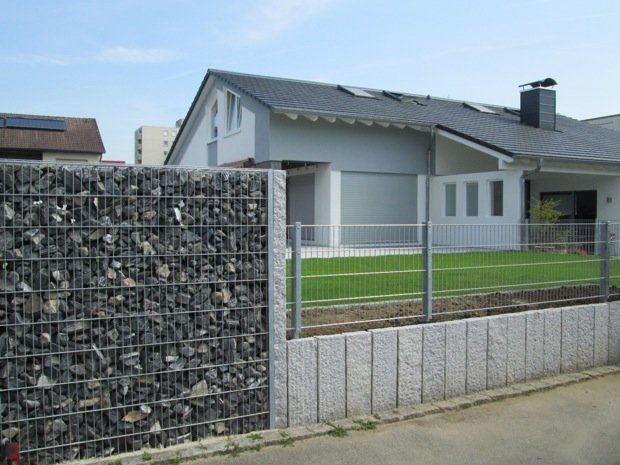 Ein Haus hinter einem Zaun mit vielen Steinen darauf