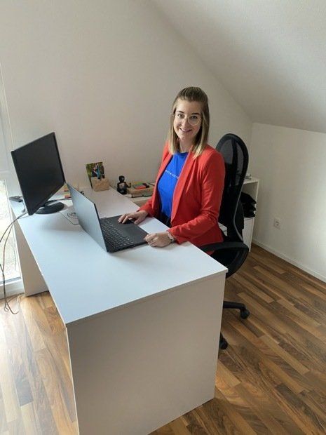 Eine Frau sitzt an einem Schreibtisch, auf dem ein Laptop steht.