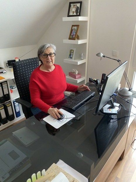 Eine Frau in einem roten Pullover sitzt an einem Schreibtisch mit einem Computer