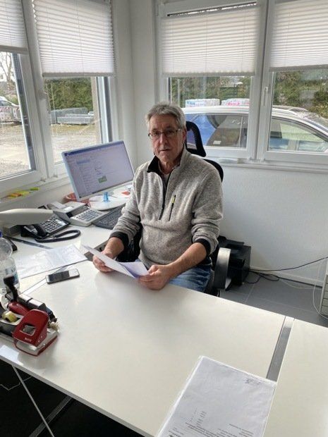 Ein Mann sitzt an einem Schreibtisch vor einem Computer.