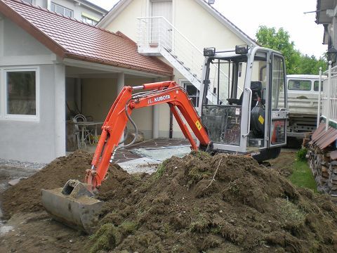 Ein Bagger gräbt ein Loch vor einem Haus