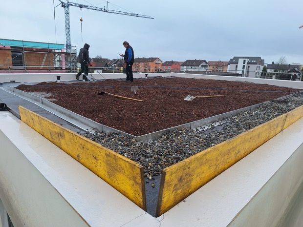 Vor einem im Bau befindlichen Gebäude liegt ein großer Erdhaufen.