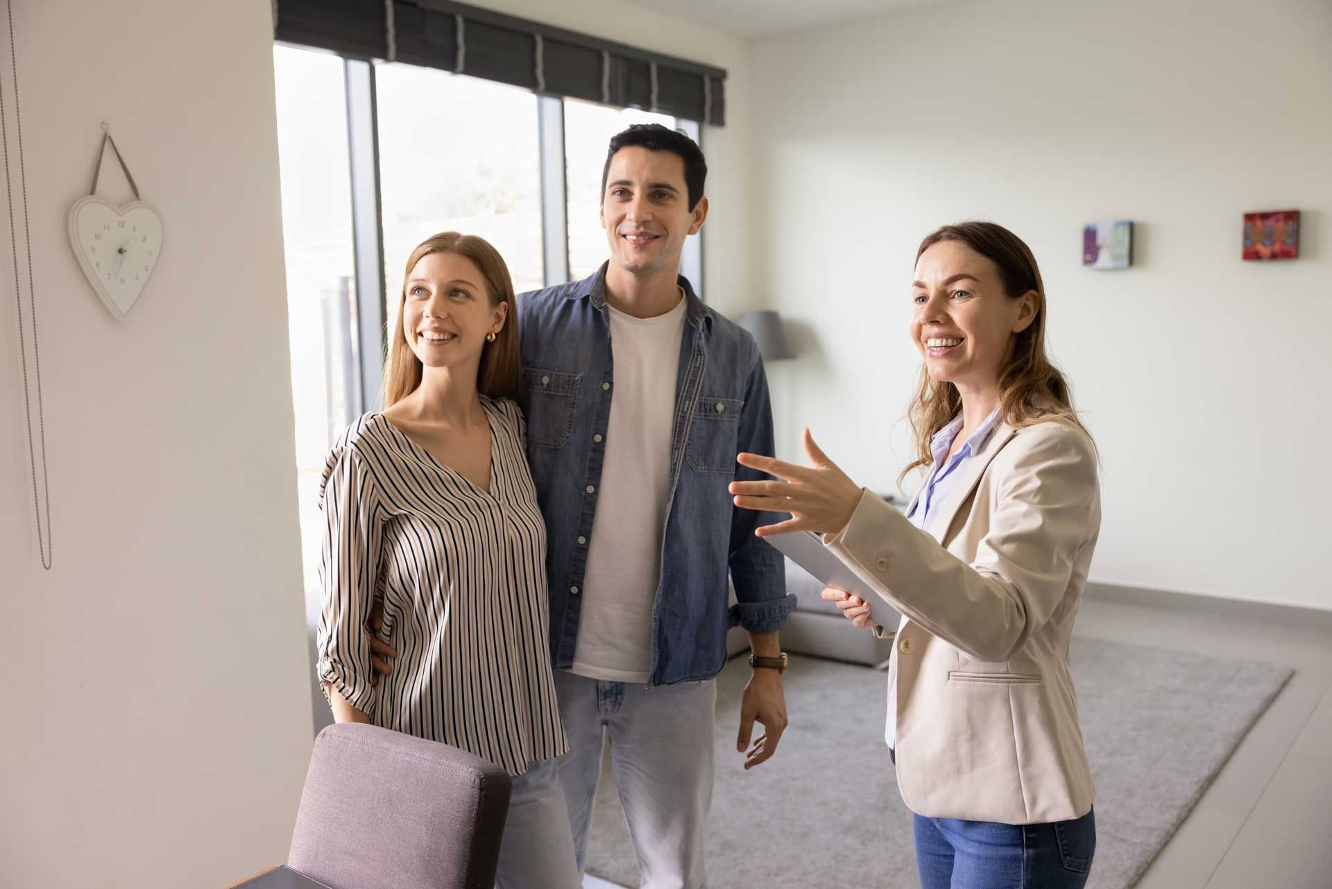 Real estate agent showing a couple a room in a modern apartment.