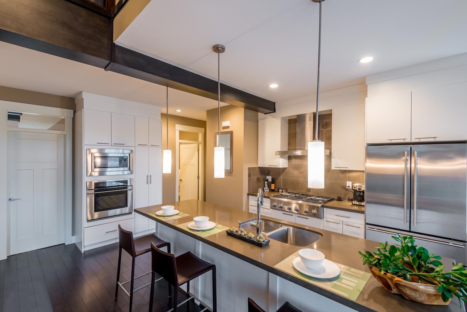 Modern kitchen with white cabinets, stainless steel appliances, and a gray island with seating.