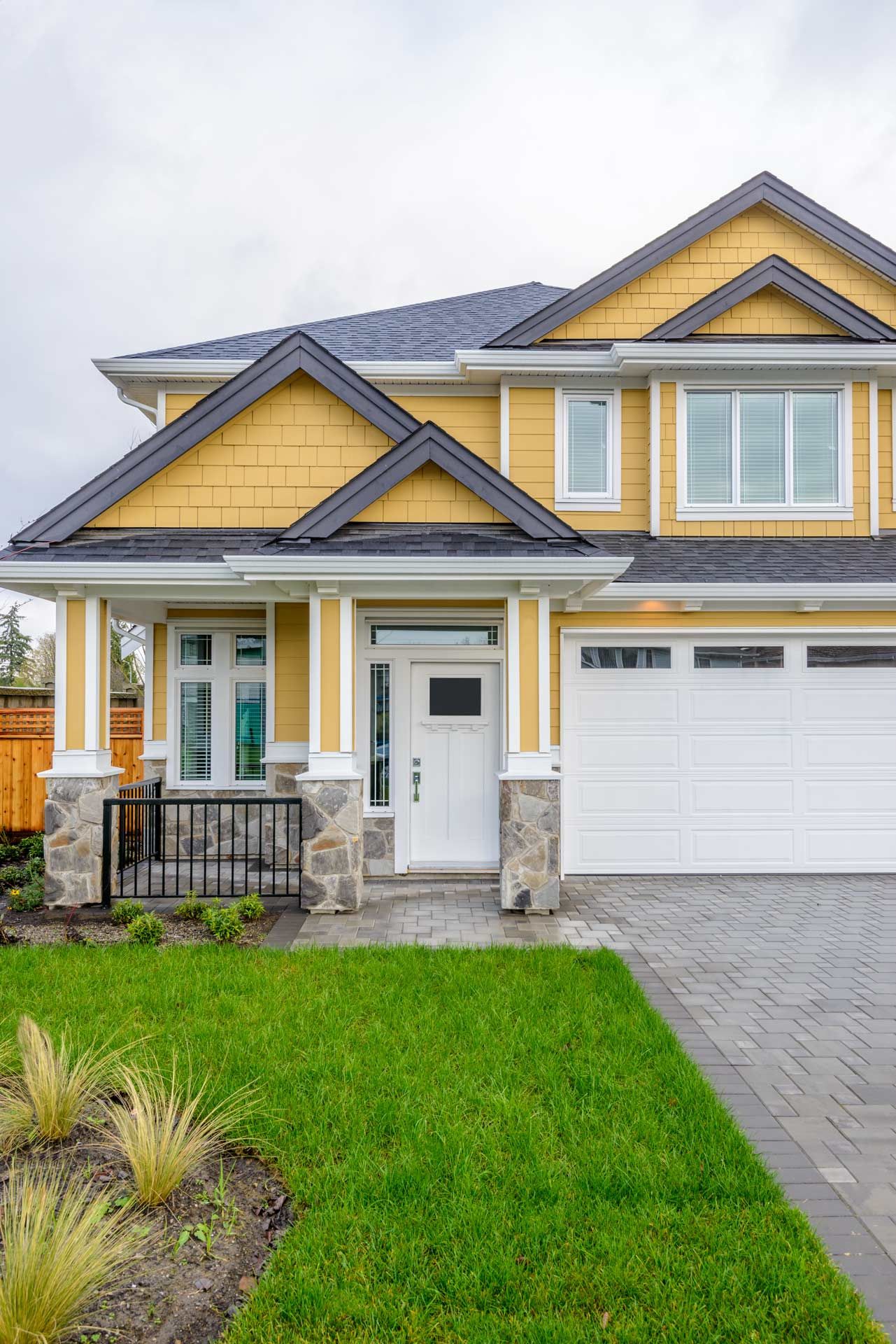 Yellow two-story house with white trim, gray roof, and a green lawn.