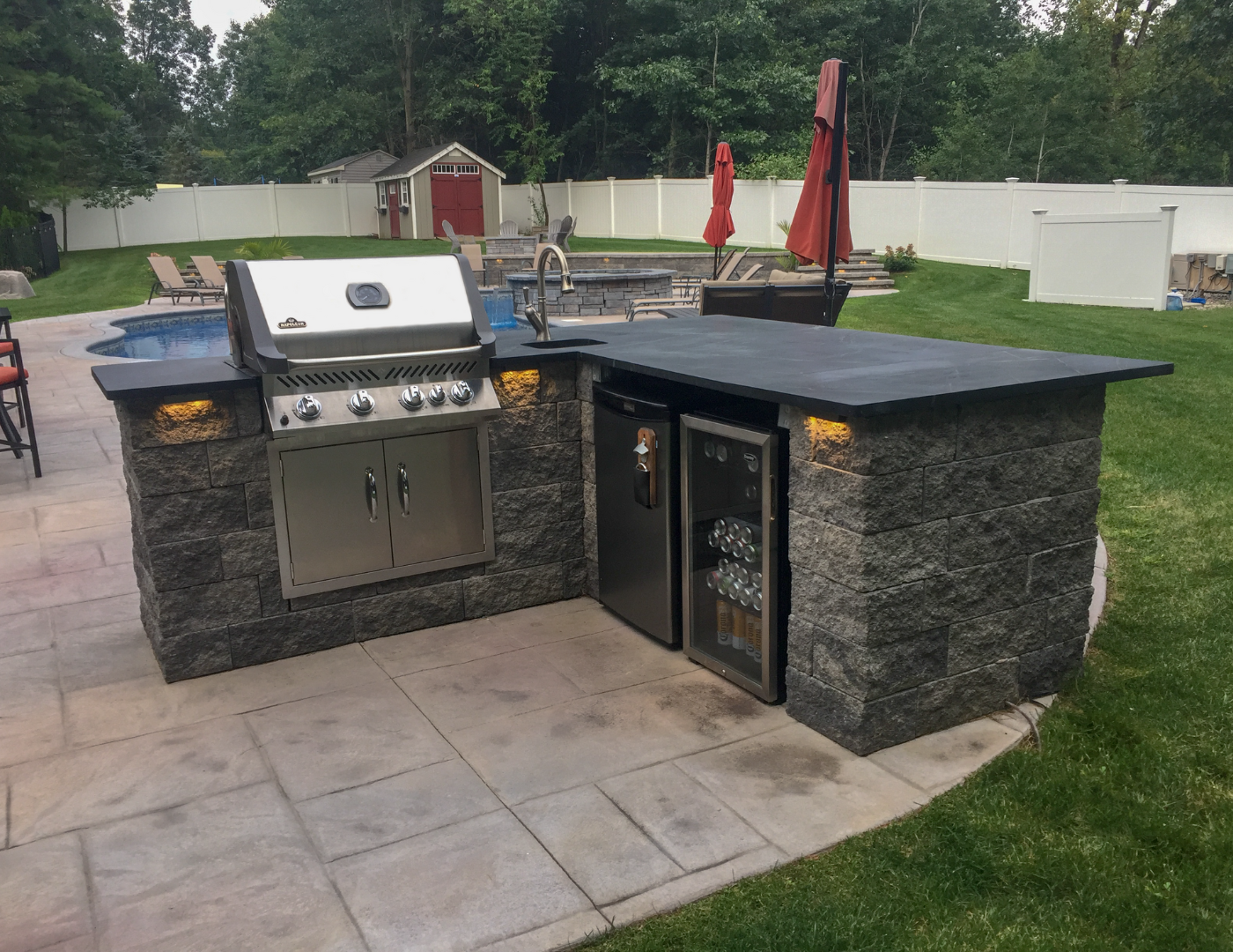 There is a grill and a refrigerator in the backyard.