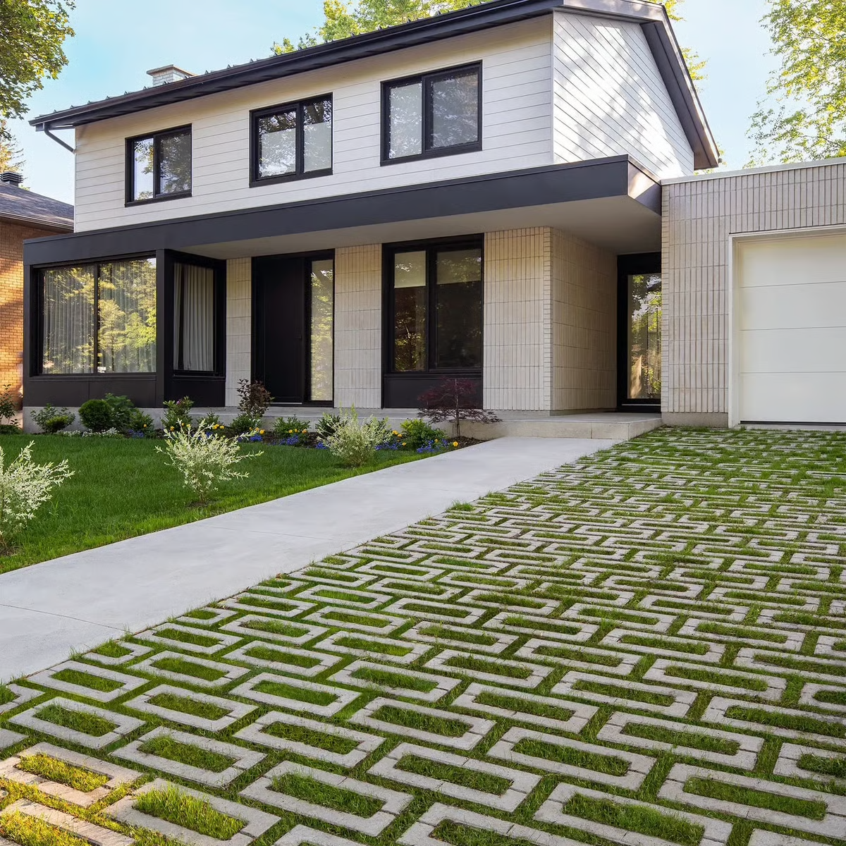 Modern hoouse with a patterned driveway, front lawn, and garage under a clear sky