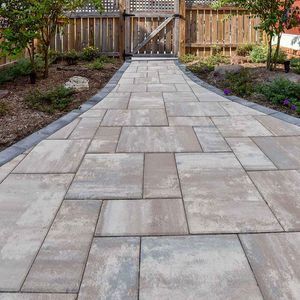 A brick walkway leading to a wooden gate in a backyard.