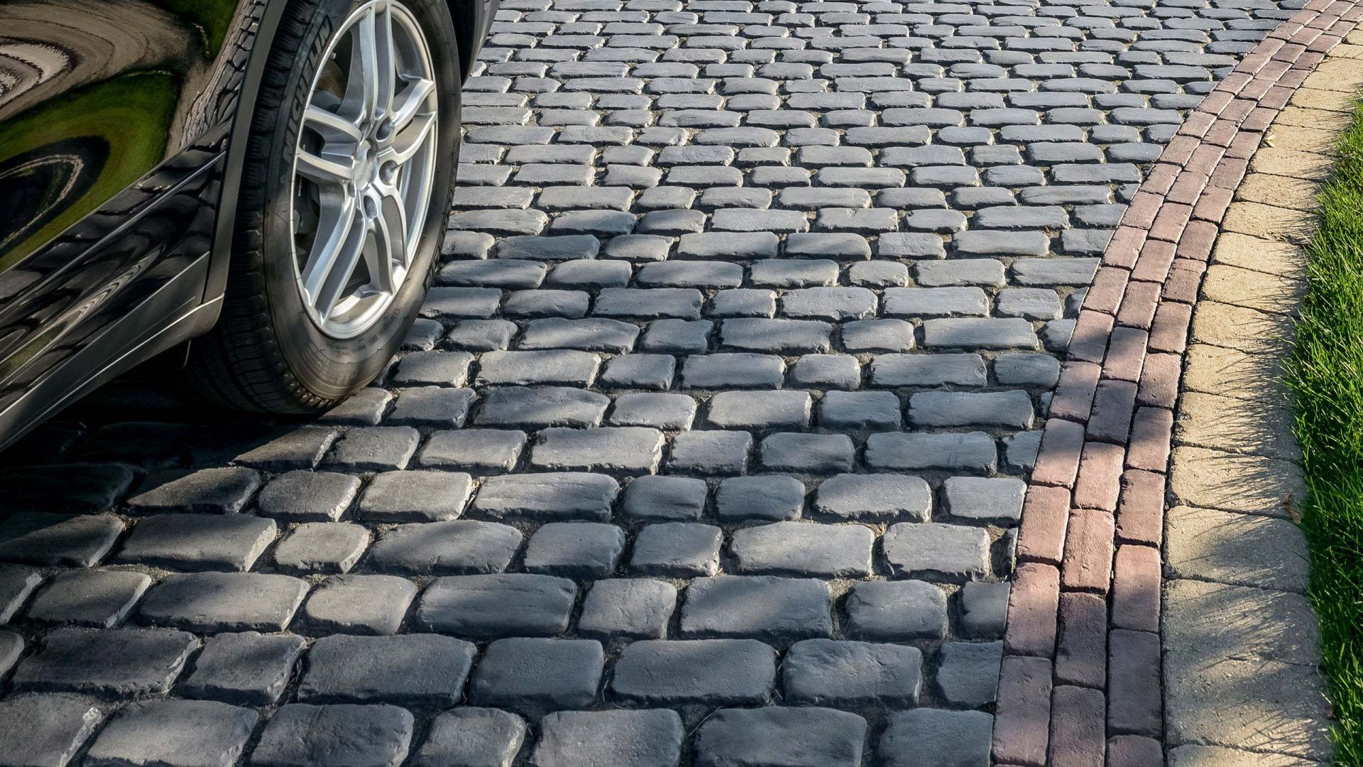 A car is parked on a cobblestone driveway.