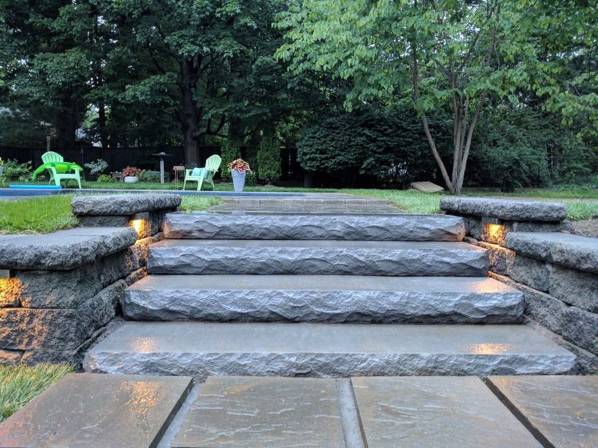 A set of stairs leading up to a backyard with chairs in the background.