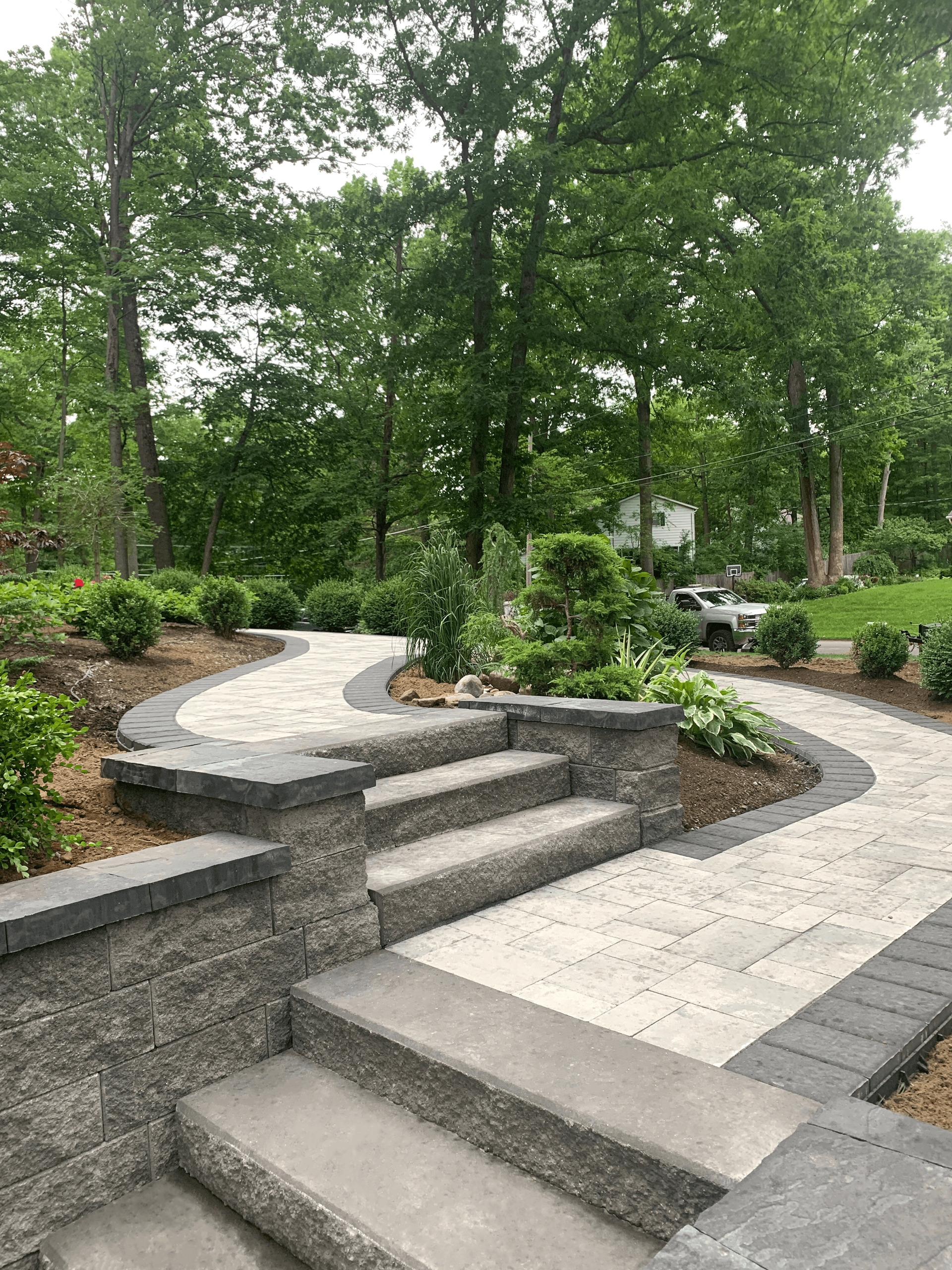 A stone walkway with stairs leading up to a lush green forest.
