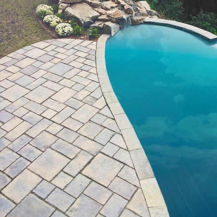 A swimming pool with a brick walkway surrounding it