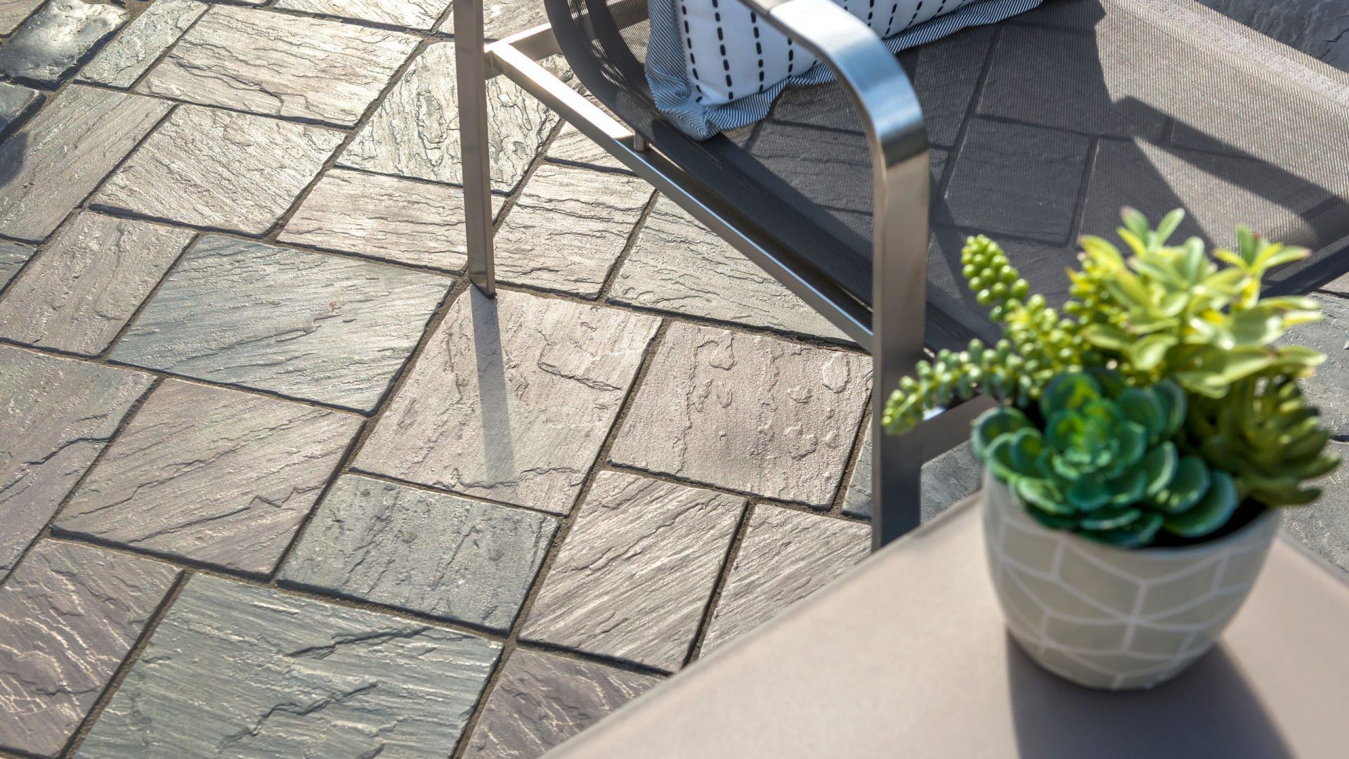 A potted plant is sitting on a table next to a chair on a patio.