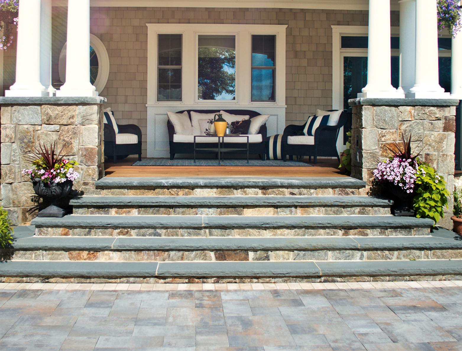 A stone porch with a couch and chairs on it