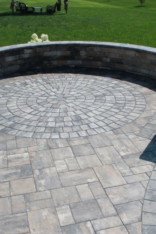 A brick patio with a circular design in the middle