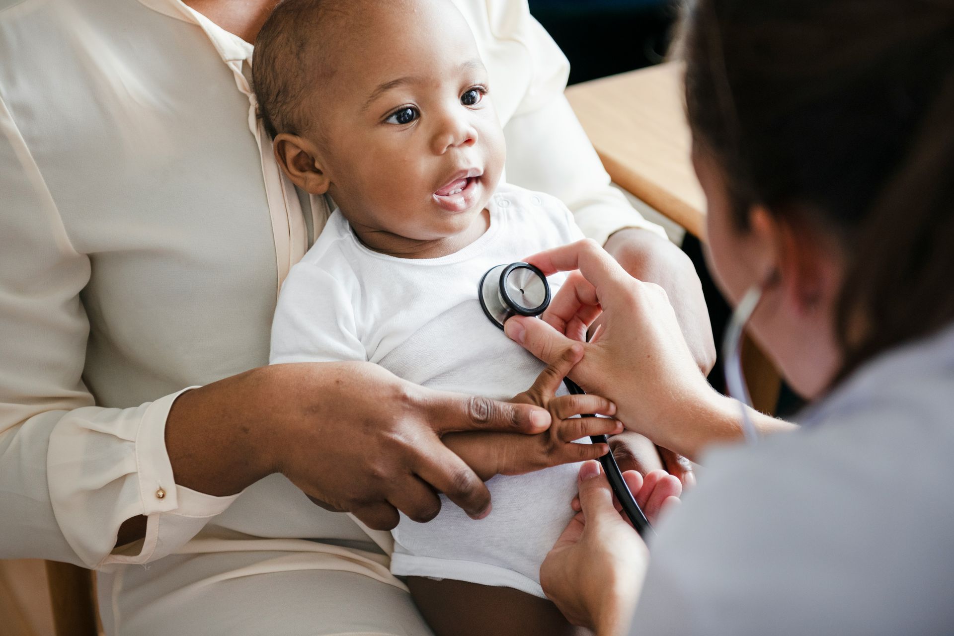 A baby is being examined by a doctor with a stethoscope.