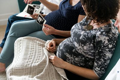 A group of pregnant women are sitting on a couch looking at an ultrasound.