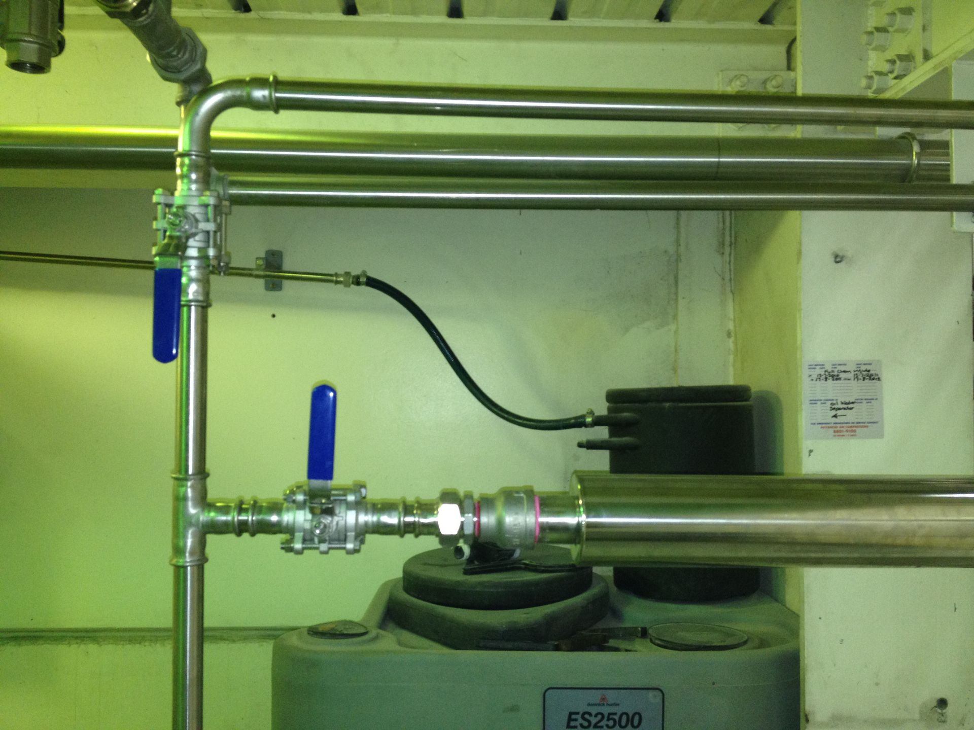 A worker in a hard hat and safety vest inspects pipes and valves in a mechanical room.Orange NSW