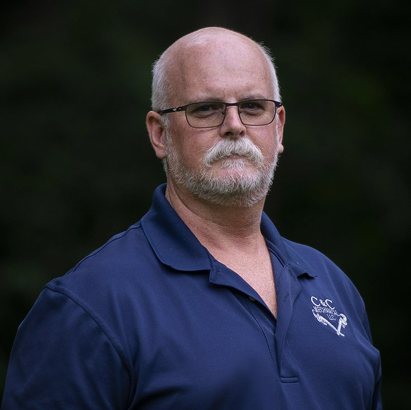 A man with a beard and glasses is wearing a blue shirt.