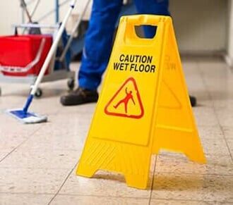 Worker Mopping Floor With Wet Floor Caution Sign — Carpet Cleaning in Pottsville, PA