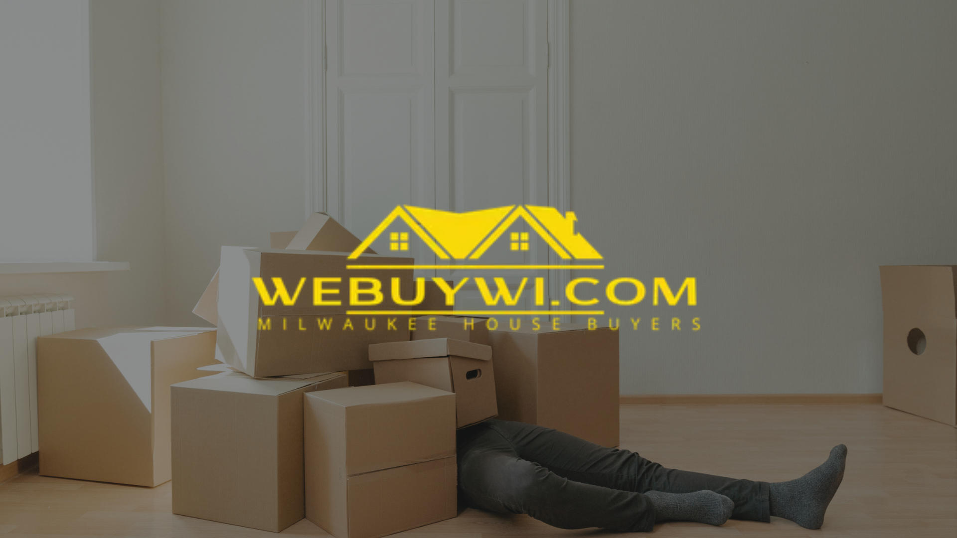 Person sitting near moving boxes, with one over their head. 