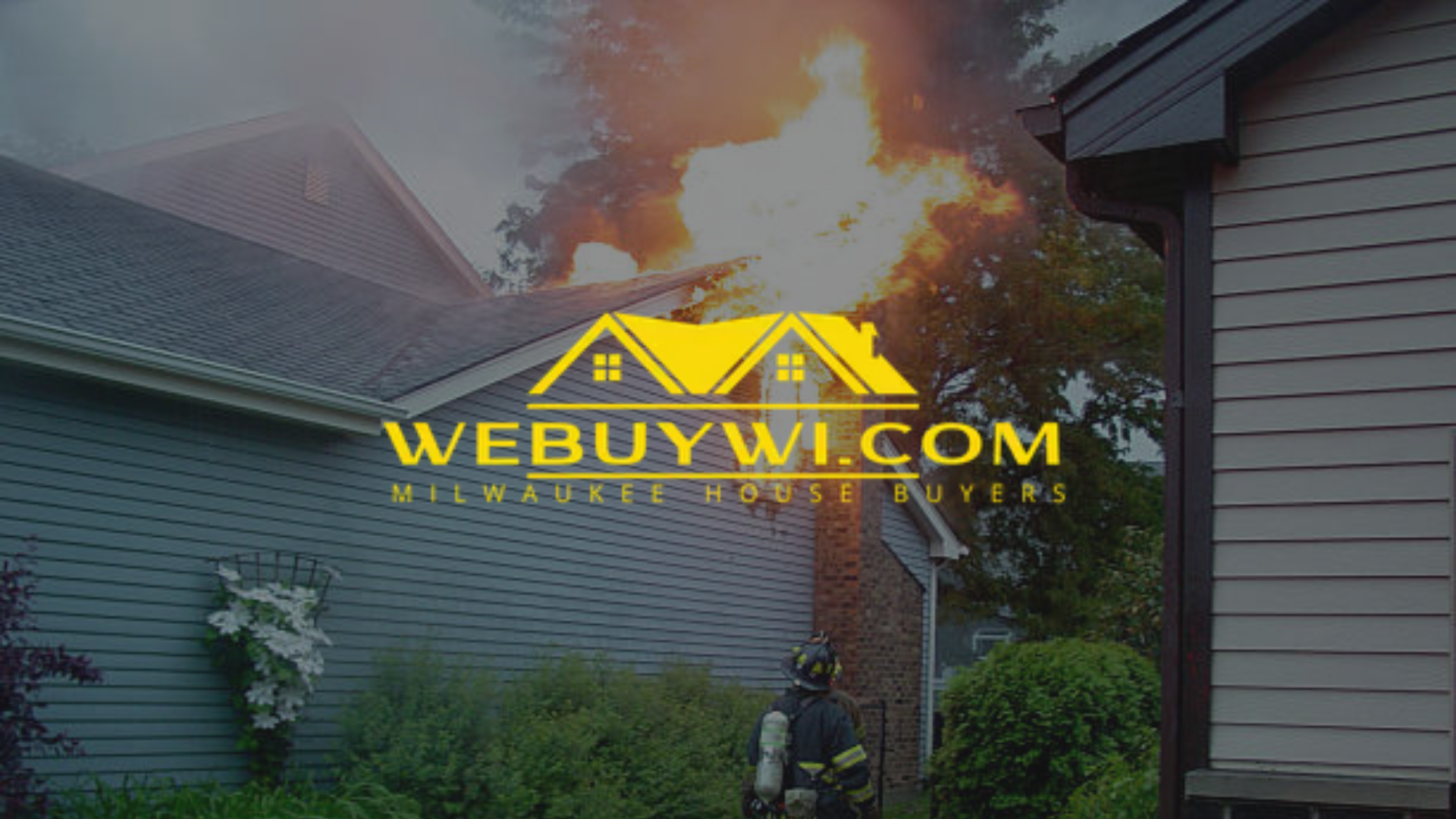 A house on fire, with a firefighter in foreground and a 