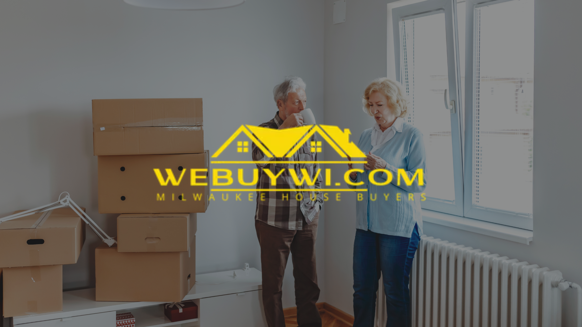 Couple in empty room with moving boxes, looking at papers. Website logo 