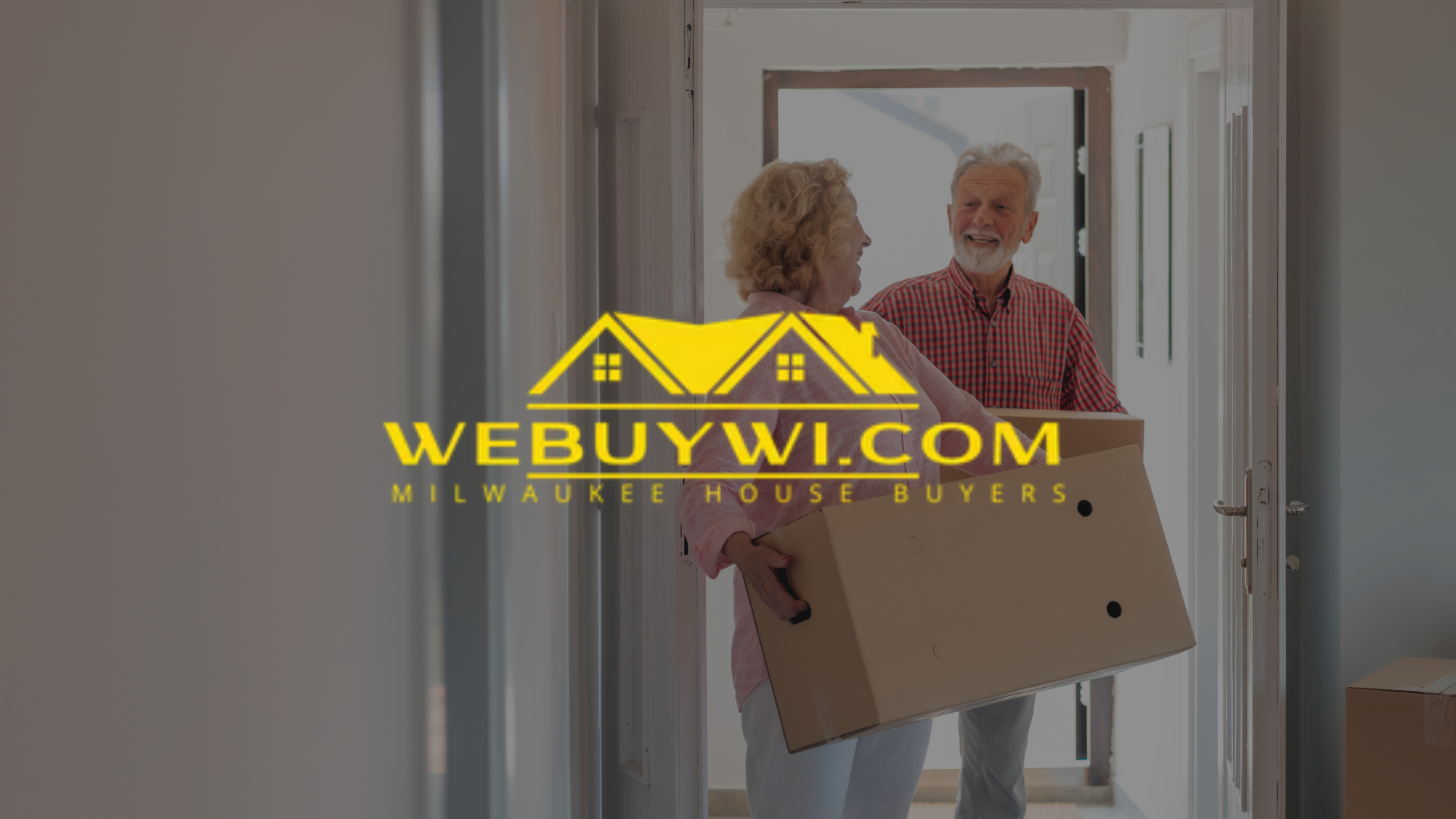 A couple carrying a moving box into a doorway, likely moving. The logo 