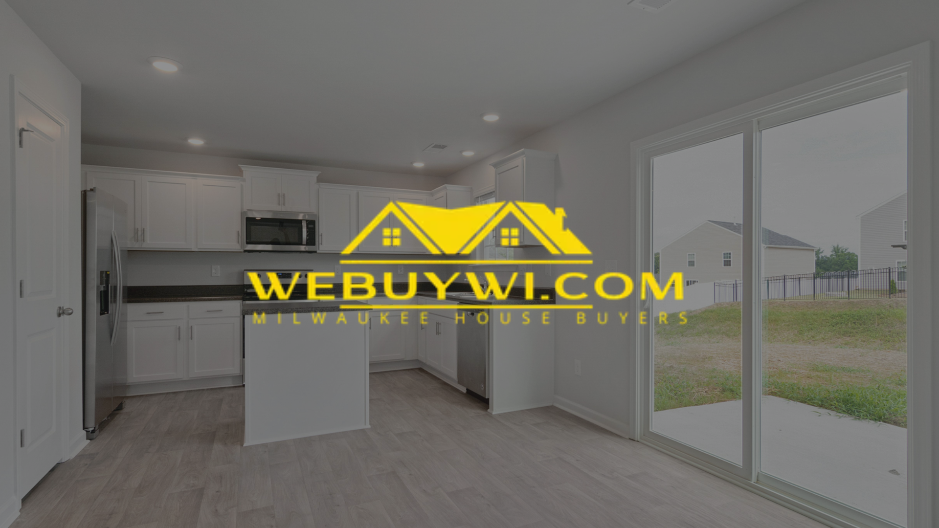 Interior kitchen with white cabinets, dark countertops, and large sliding glass door.