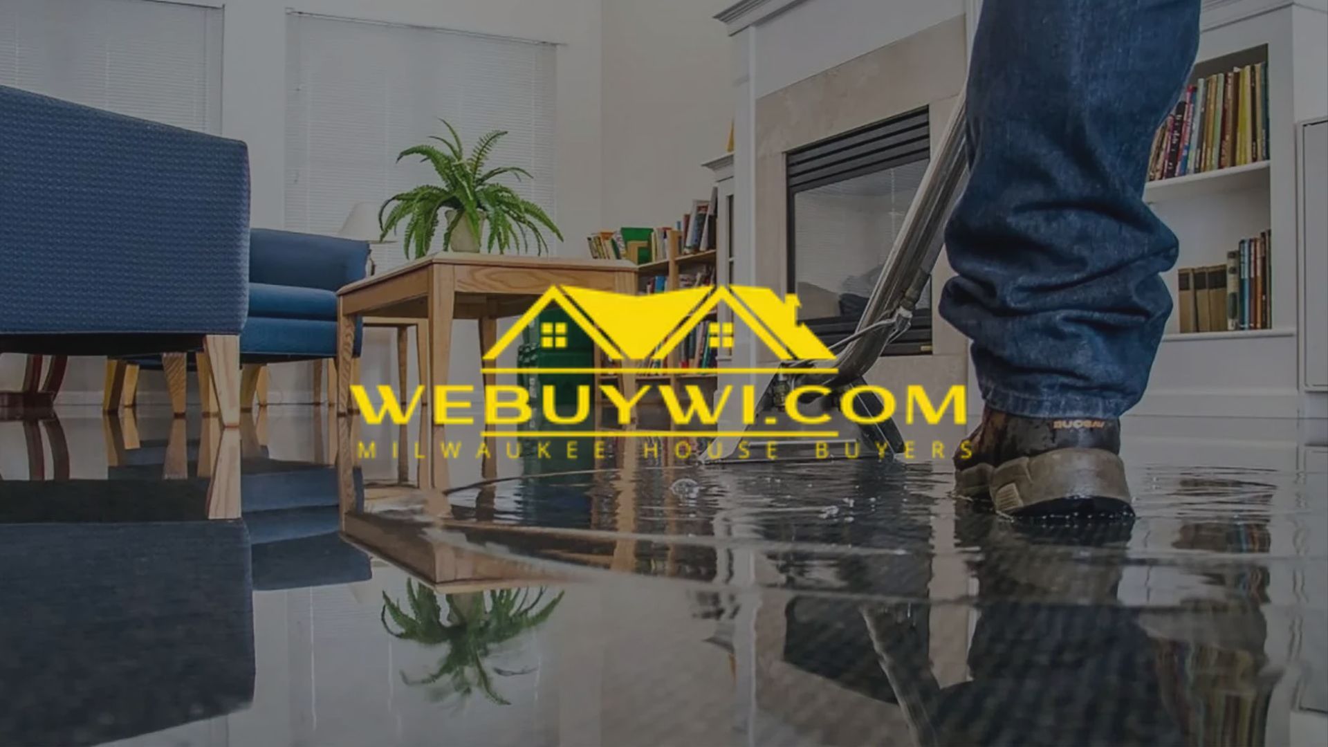 Person mopping a flooded living room floor; a logo with yellow houses is visible.