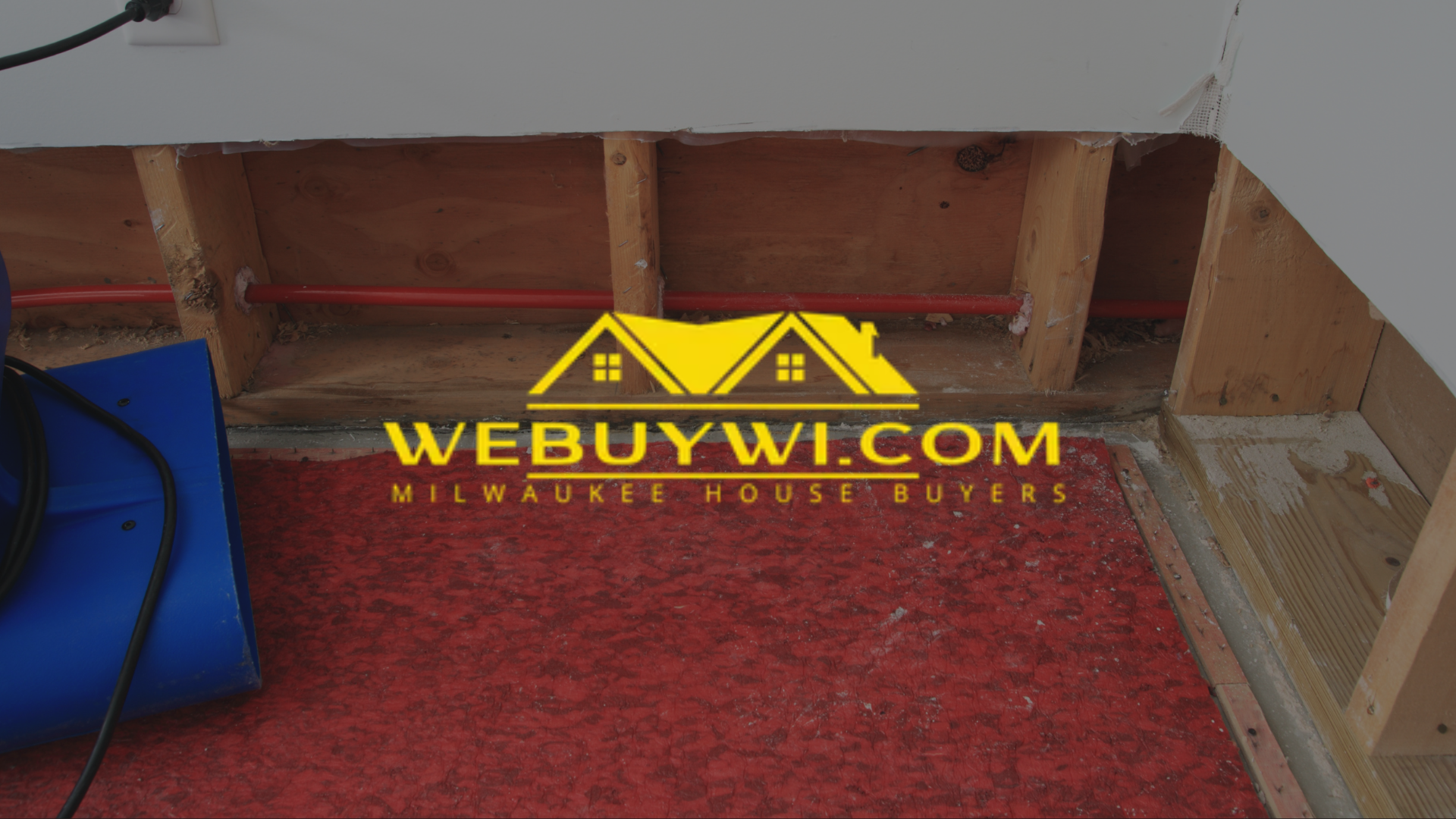 Exposed wall studs, red carpet, and blue equipment, potentially flood damage.