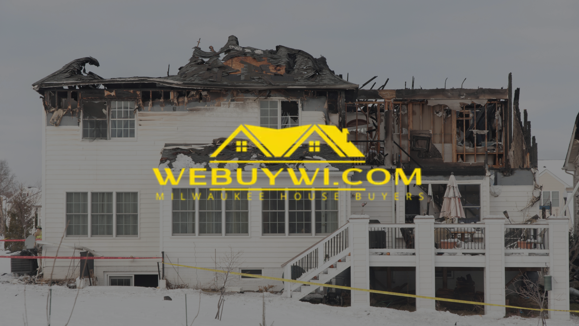 House severely damaged by fire, with charred roof and white siding. Snow on the ground.