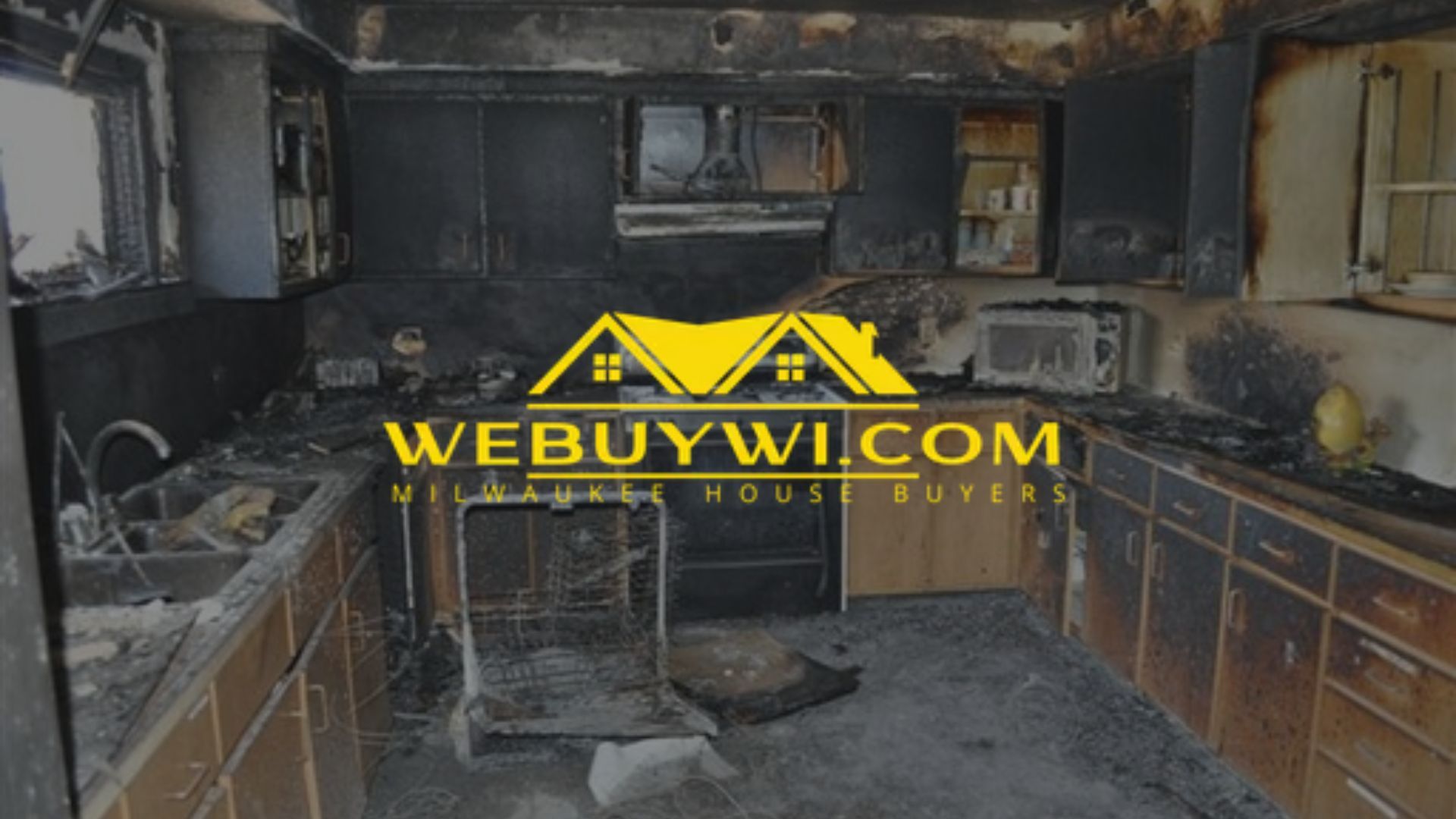 Burned kitchen interior, dark walls, debris, and appliance damage from a fire.