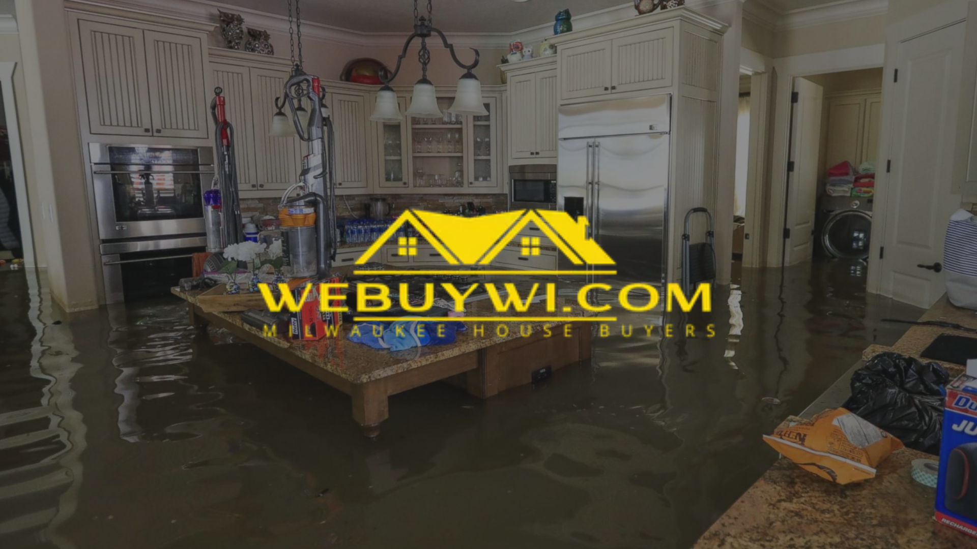 Flooded kitchen; water covers floor. Cabinets and appliances are visible. A logo for