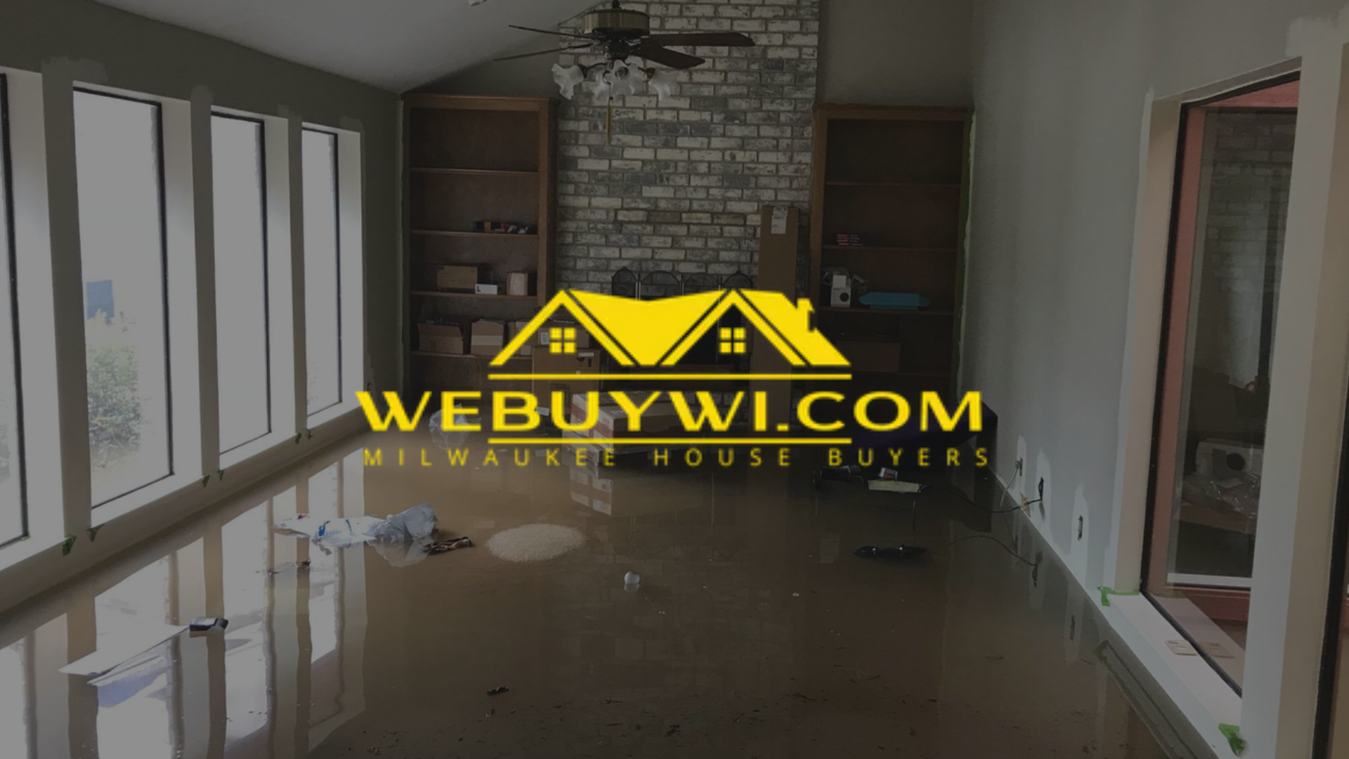 A room with a polished floor, large windows, fireplace, and the