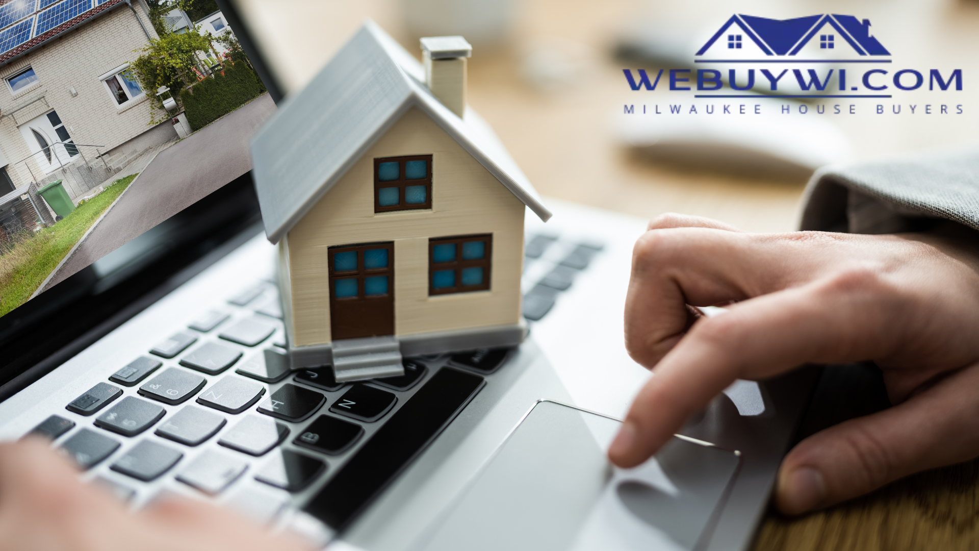 A person is typing on a laptop with a model house on the keyboard