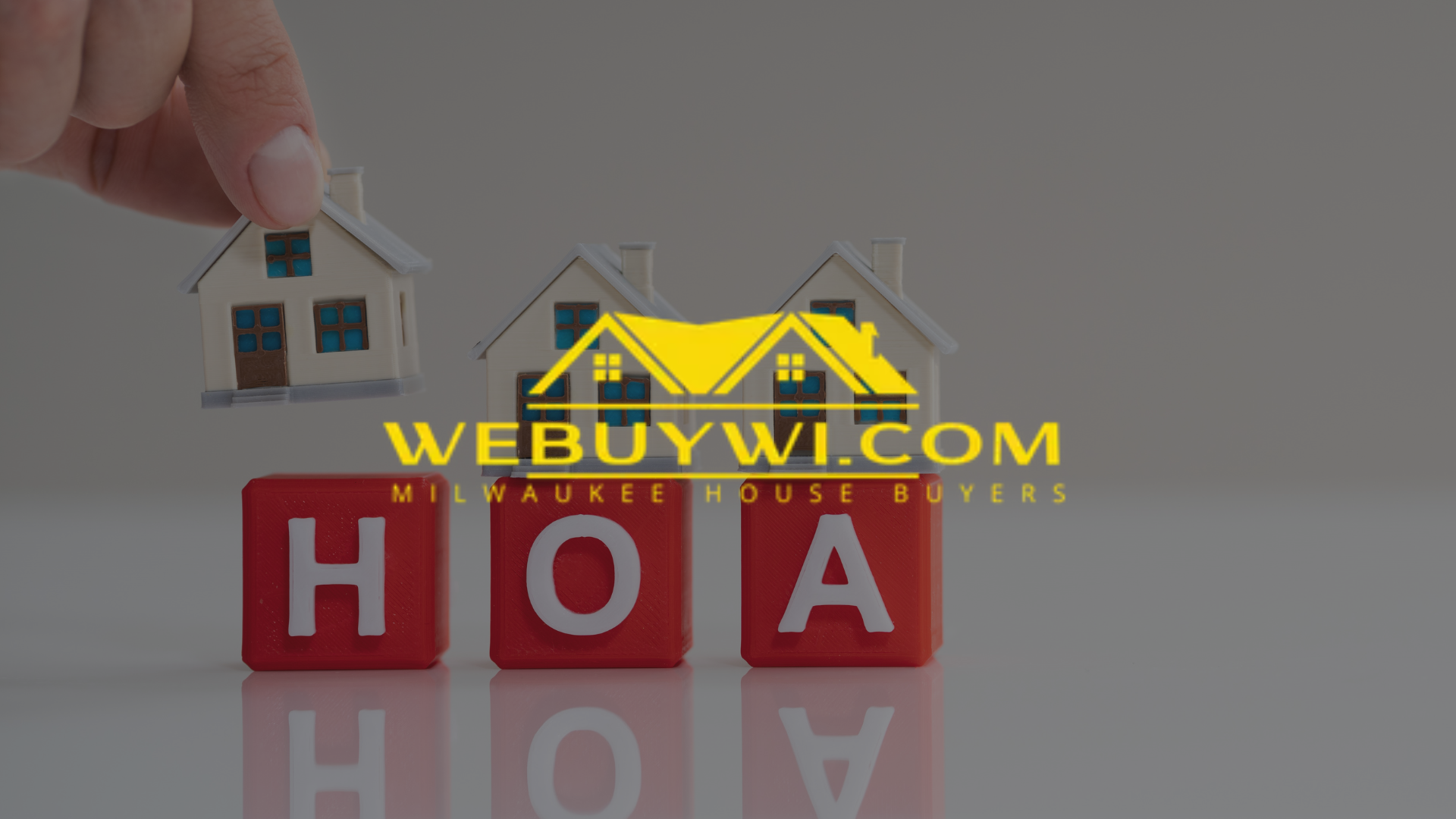 Hand placing a miniature house over blocks spelling 